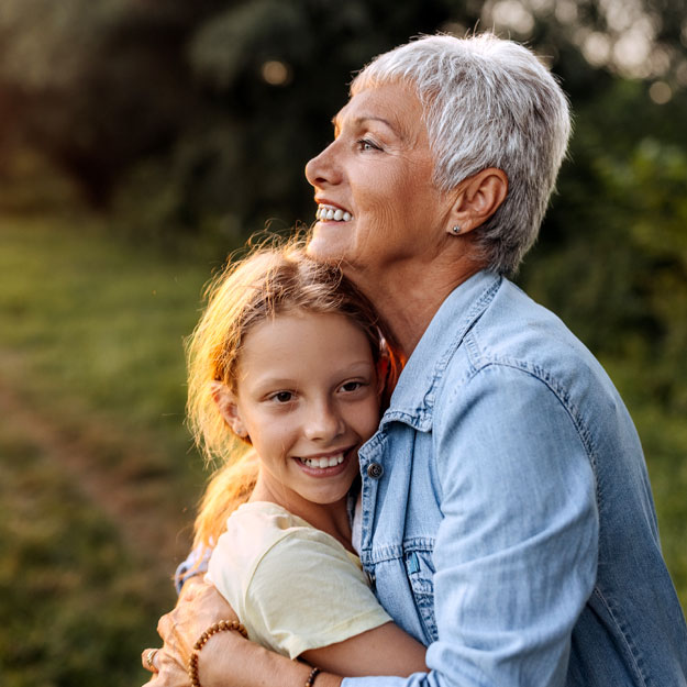 Woman with short-cropped white hair hugging young girl