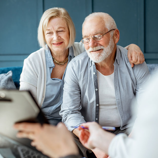 Doctor reviewing documents on a clipboard with an older man and woman.